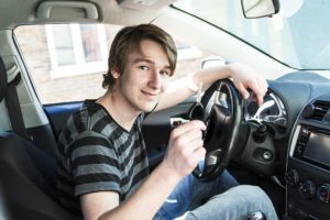 A Teenage boy and new driver behind wheel of his car
